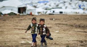 Syrian boys, whose family fled their home in Idlib, walk to their tent, at a camp for displaced Syrians, in the village of Atmeh, Syria, Monday, Dec. 10, 2012.jpg